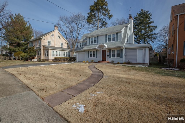 view of front of home with concrete driveway, a front lawn, and a chimney