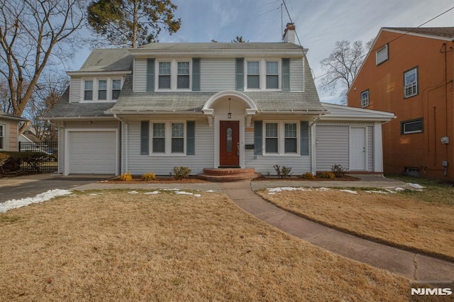 view of front of house with concrete driveway, a garage, a front yard, and roof with shingles