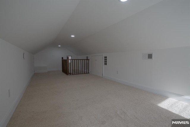additional living space featuring light colored carpet, vaulted ceiling, baseboards, and recessed lighting