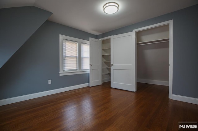 unfurnished bedroom featuring lofted ceiling, baseboards, and wood finished floors