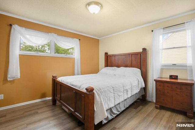 bedroom featuring light wood-style floors, multiple windows, crown molding, and baseboards