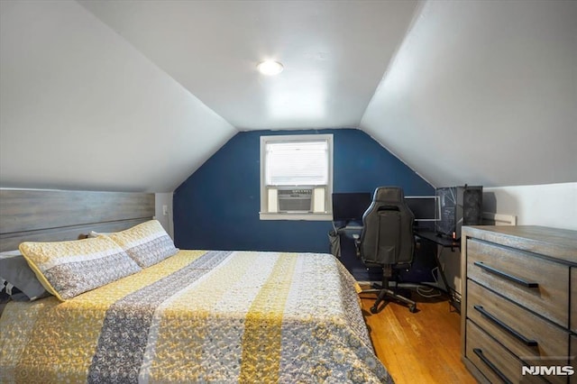 bedroom with wood finished floors, cooling unit, and lofted ceiling
