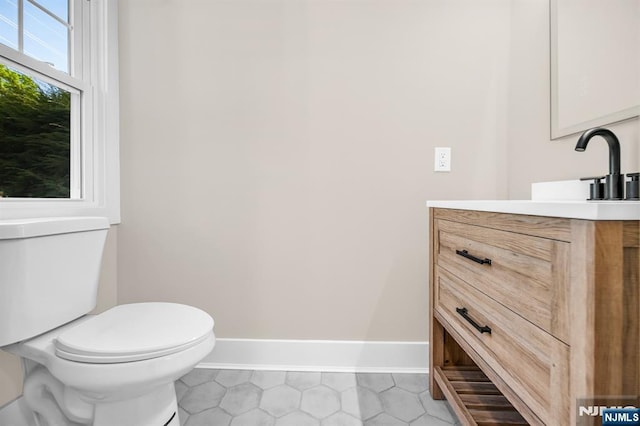 bathroom featuring vanity, tile patterned flooring, baseboards, and toilet