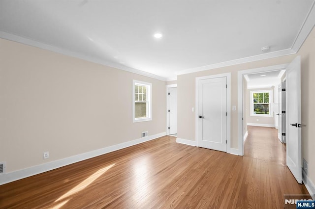 empty room featuring ornamental molding, light wood finished floors, baseboards, and recessed lighting