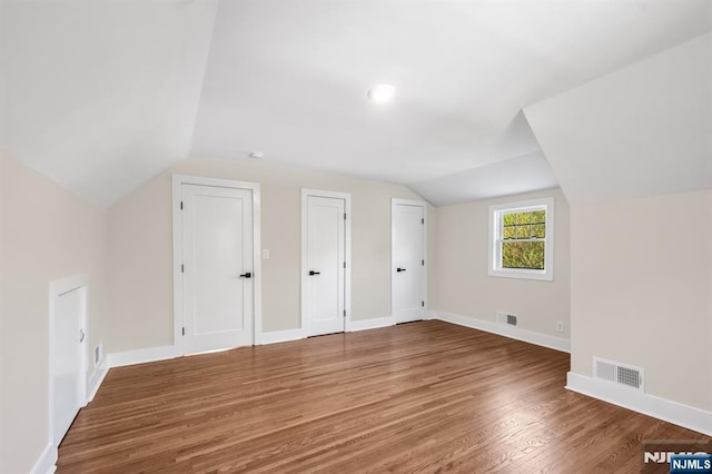 additional living space featuring lofted ceiling, wood finished floors, and baseboards