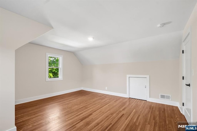 bonus room featuring wood finished floors, vaulted ceiling, and baseboards