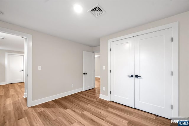 unfurnished bedroom featuring light wood-type flooring, baseboards, and a closet
