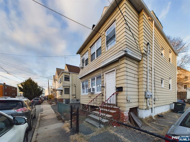 view of building exterior with entry steps, fence, and cooling unit