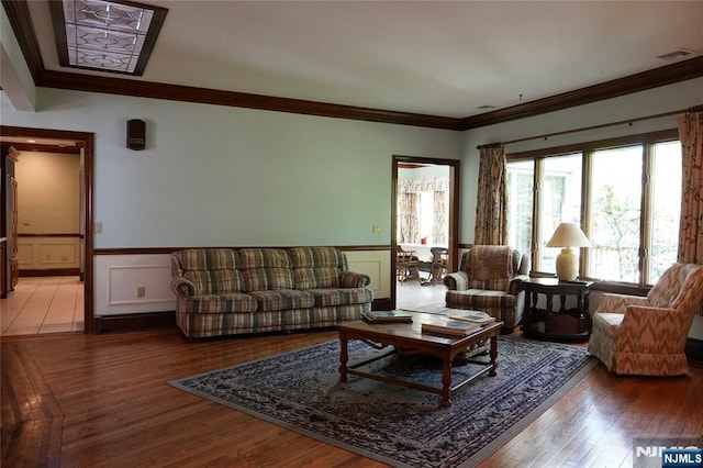 living room with crown molding, wainscoting, and wood finished floors