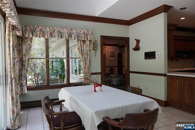dining space with light tile patterned floors, ornamental molding, plenty of natural light, and a wainscoted wall