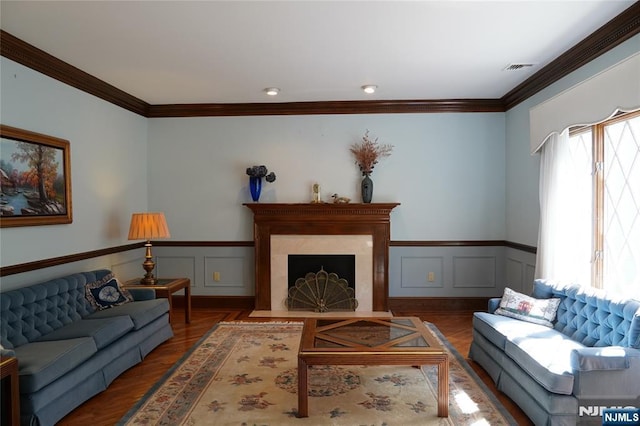 living area with wood finished floors, crown molding, wainscoting, a decorative wall, and a premium fireplace