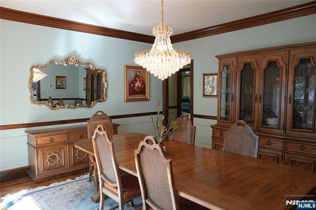 dining space with a chandelier, ornamental molding, a decorative wall, and wainscoting