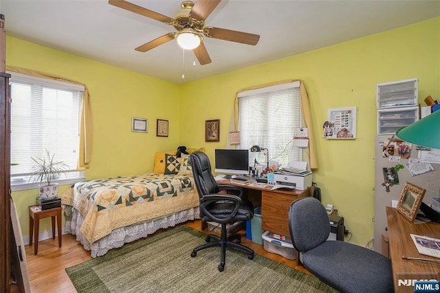 bedroom with wood finished floors, an office area, and ceiling fan