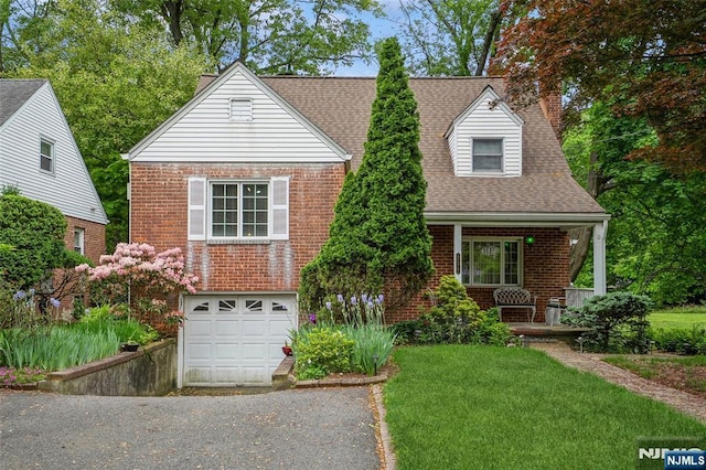view of front of house featuring asphalt driveway, brick siding, a chimney, a porch, and an attached garage