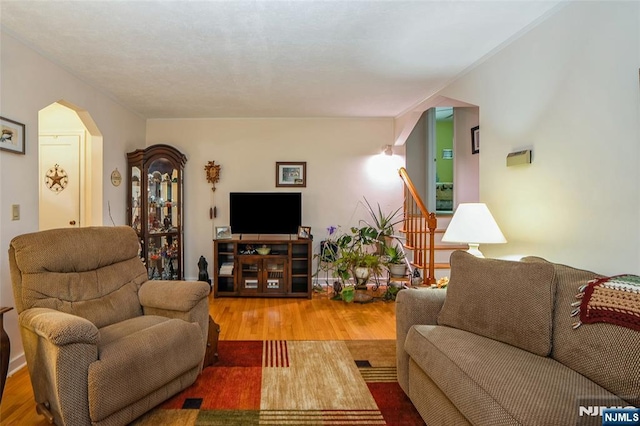 living room with arched walkways, wood finished floors, and stairs
