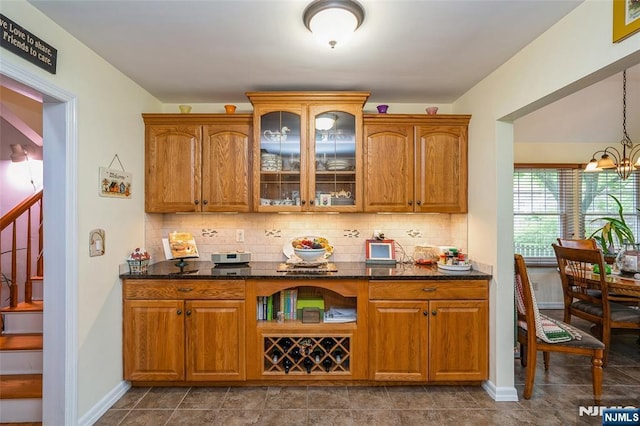 bar area featuring backsplash, stairway, a chandelier, and baseboards