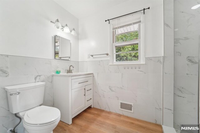 7 Swan Ter, Wayne, NJ 07470 - full bathroom featuring tile walls, vanity, toilet, wood finished floors, and a wainscoted wall