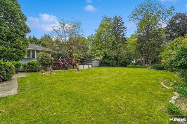 7 Swan Ter, Wayne, NJ 07470 - view of grassy yard featuring stairway, a deck, and view of wooded area