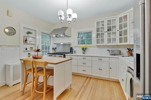 121 Beverly Rd, Montclair, NJ 07043 - kitchen featuring wall chimney range hood, stainless steel fridge with ice dispenser, wood counters, white cabinetry, and tile walls