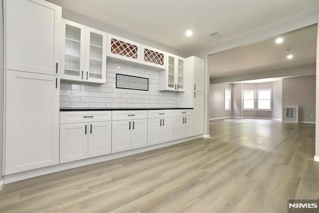 kitchen with white cabinets, dark countertops, recessed lighting, open floor plan, and backsplash