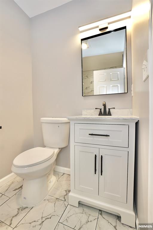 bathroom featuring marble finish flooring, baseboards, toilet, and vanity