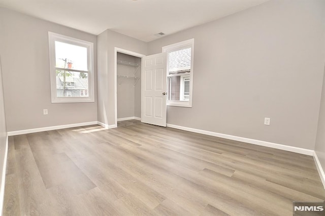 unfurnished bedroom with baseboards, wood finished floors, and a closet