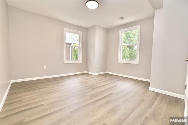 empty room with plenty of natural light, baseboards, and wood finished floors