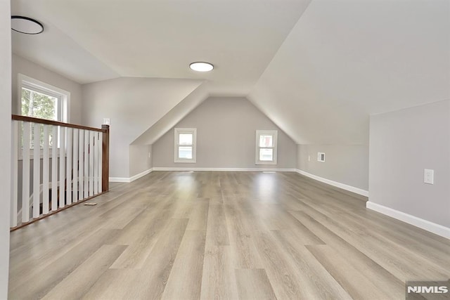 bonus room featuring wood finished floors, healthy amount of natural light, lofted ceiling, and baseboards