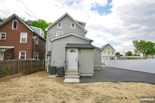 rear view of house featuring entry steps, a fenced backyard, and central air condition unit