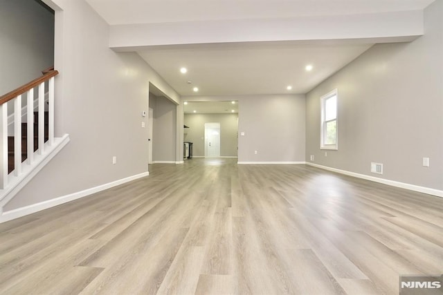 unfurnished living room featuring wood finished floors, recessed lighting, stairs, and baseboards