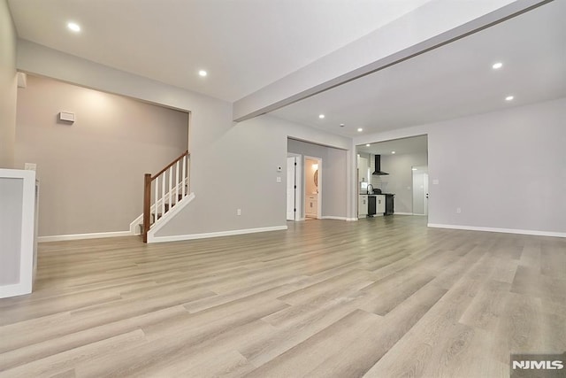 unfurnished living room featuring light wood-style flooring, stairway, recessed lighting, and baseboards