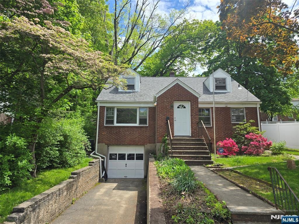 221 Warwick Ln, Leonia, NJ 07605 - cape cod home with driveway, an attached garage, brick siding, and roof with shingles