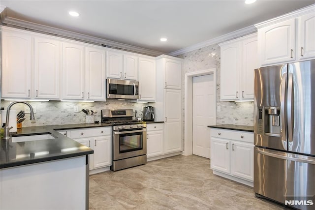 kitchen with appliances with stainless steel finishes, a sink, dark countertops, ornamental molding, and white cabinetry