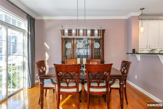 dining room featuring healthy amount of natural light, light wood finished floors, baseboards, and ornamental molding