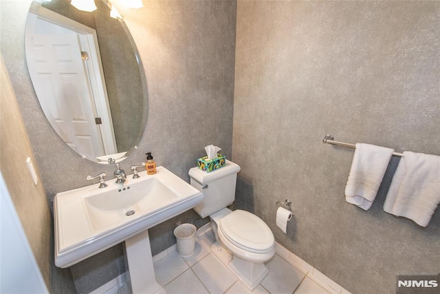half bathroom featuring tile patterned floors, toilet, and a sink