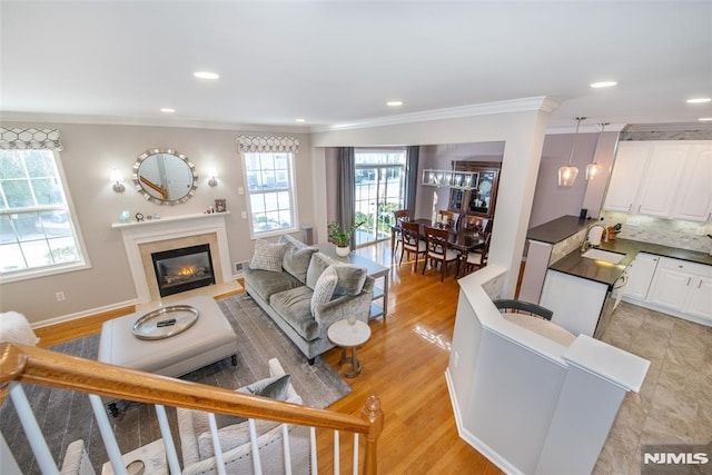 living area featuring ornamental molding, a fireplace with flush hearth, recessed lighting, light wood-type flooring, and baseboards
