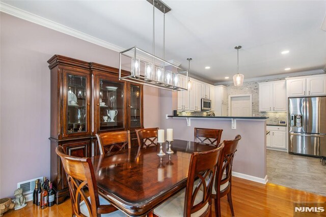 dining area featuring ornamental molding, recessed lighting, and light wood finished floors