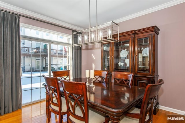 dining area featuring crown molding, wood finished floors, and baseboards