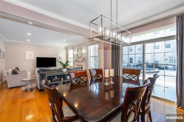 dining area featuring ornamental molding, light wood-style flooring, recessed lighting, and a fireplace