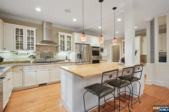 125 Bellevue Ave, Montclair, NJ 07043 - kitchen featuring stainless steel appliances, wall chimney exhaust hood, light wood finished floors, ornamental molding, and a center island