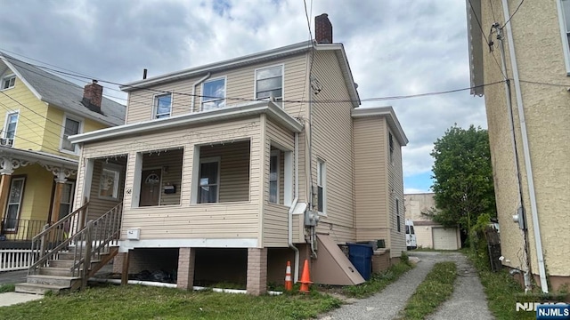 view of front of home featuring a chimney and covered porch