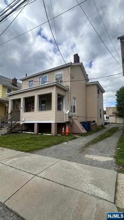 back of property with driveway, a chimney, and a porch