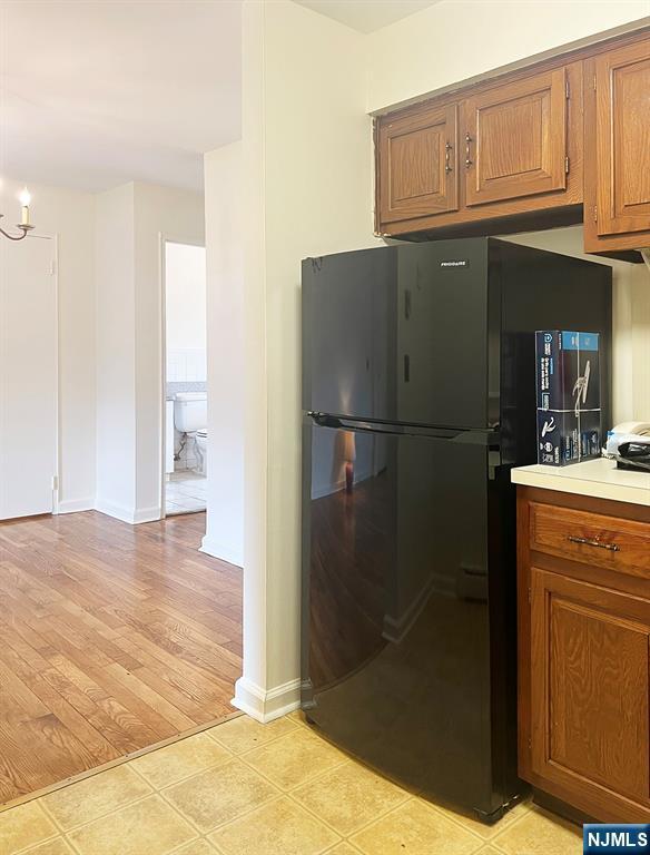 109 N Maple, Park Ridge, NJ 07656 - kitchen featuring freestanding refrigerator, brown cabinets, light countertops, baseboards, and a chandelier