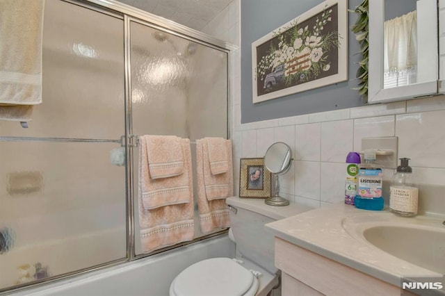 127 Brill St, Newark, NJ 07105 - bathroom featuring bath / shower combo with glass door, vanity, toilet, backsplash, and tile walls