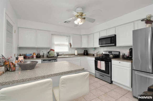 127 Brill St, Newark, NJ 07105 - kitchen with appliances with stainless steel finishes, white cabinetry, decorative backsplash, and light tile patterned floors