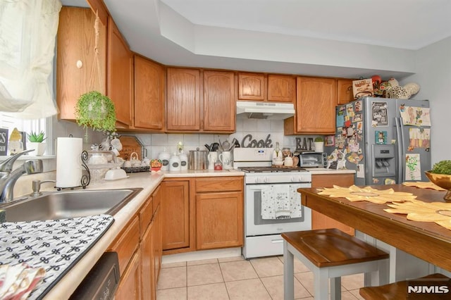 127 Brill St, Newark, NJ 07105 - kitchen with white gas range oven, under cabinet range hood, stainless steel fridge, a sink, and light countertops