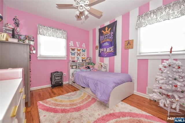 bedroom with wood finished floors, a wood stove, and baseboards