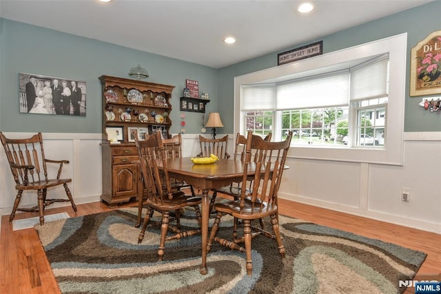 dining room with wood finished floors, a wainscoted wall, a decorative wall, and recessed lighting