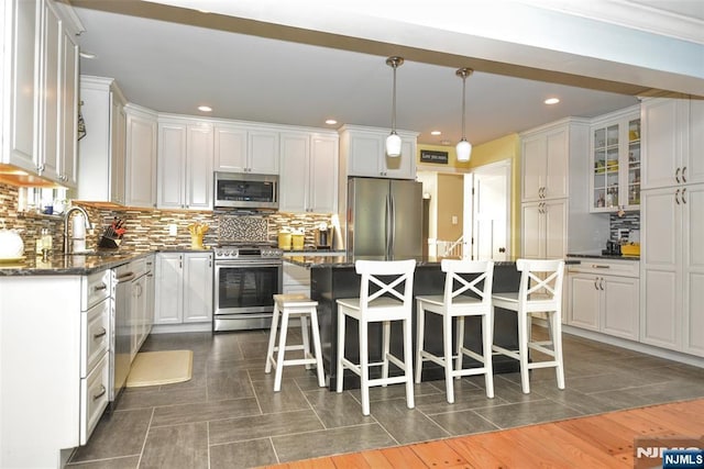 kitchen with appliances with stainless steel finishes, a sink, a kitchen breakfast bar, white cabinets, and recessed lighting