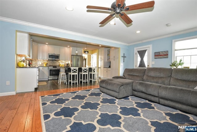 living room with hardwood / wood-style flooring, crown molding, ceiling fan, recessed lighting, and baseboards